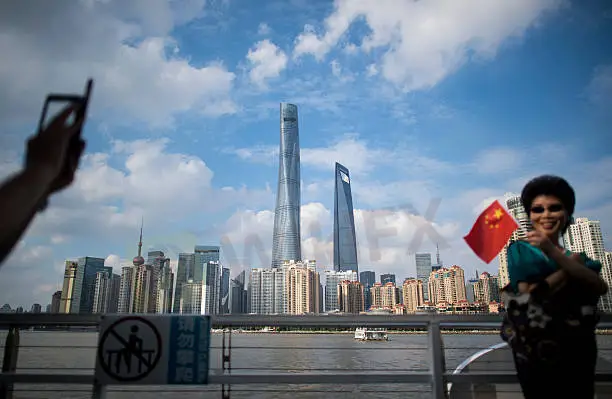 woman-poses-for-a-picture-with-a-chinese-flag-in-front-of-the-skyline-picture-id611936530.jpg